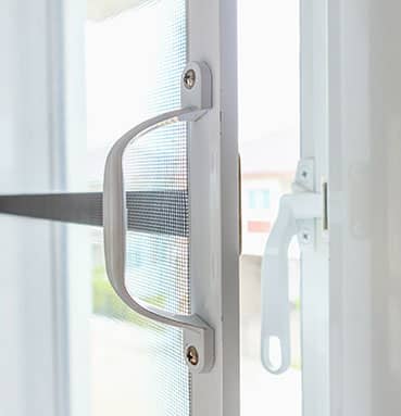 Ein geöffnetes Fenster mit einem fest montierten Fliegengitter, das einen Griff besitzt