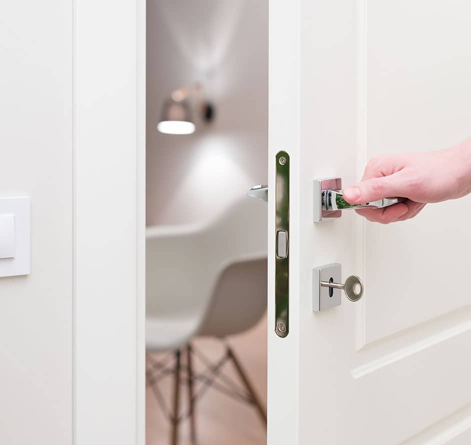 Eine Nahaufnahme einer Person, die einen Schlüssel in ein Türschloss steckt und die Tür öffnet